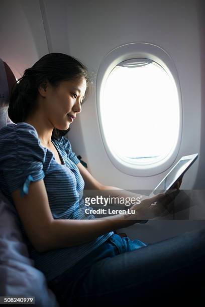girl checking digital tablet on airplane - raamplaats stockfoto's en -beelden
