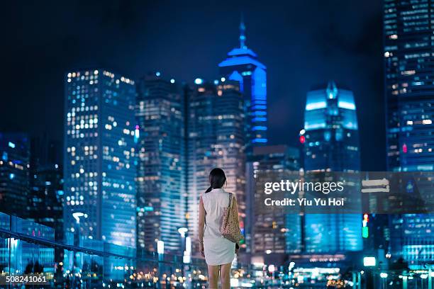 young female standing in front of modern city - city by night stock-fotos und bilder