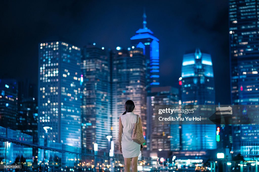 Young female standing in front of modern city