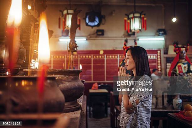 asian female praying sincerely in a chinese temple - religion stockfoto's en -beelden