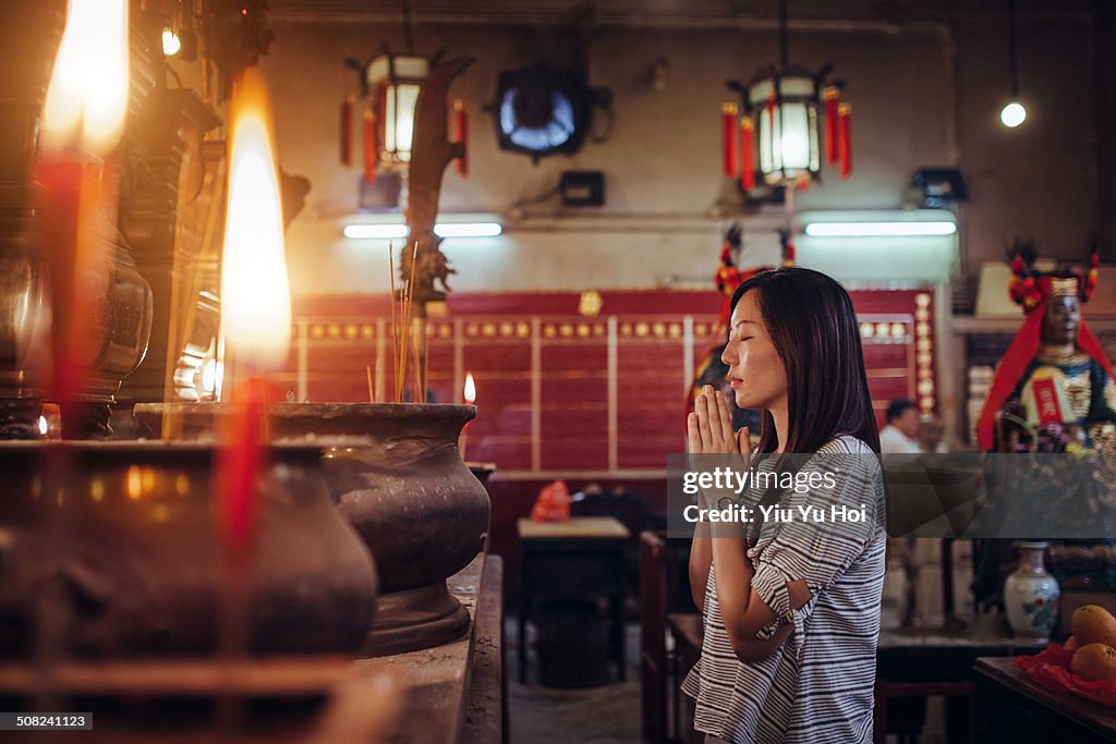 Asian female praying sincerely in a Chinese temple