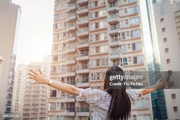 asian female overlooking city with arms wide open - open arms stock-fotos und bilder