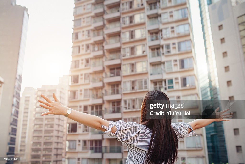 Asian female overlooking city with arms wide open