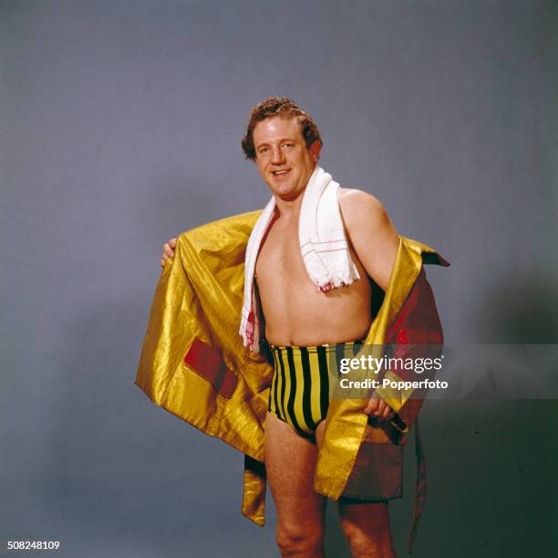 English professional wrestler Jackie Pallo posed wearing a red and gold robe, yellow and black striped trunks and a white towel around his neck in...