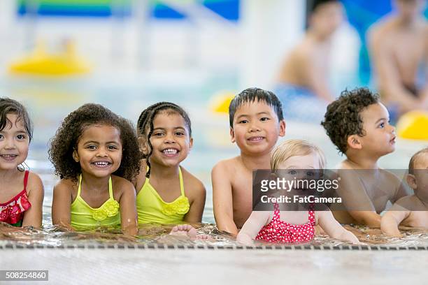 kinder sitzen in einem flachen schwimmbad - baby swimmer stock-fotos und bilder