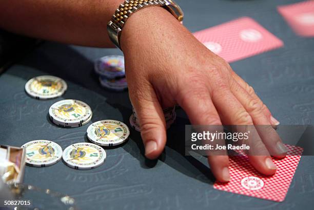 Poker player takes his cards May 11, 2004 during the grand opening for the Seminole Hard Rock Hotel and Casino in Hollywood, Florida. South Florida's...