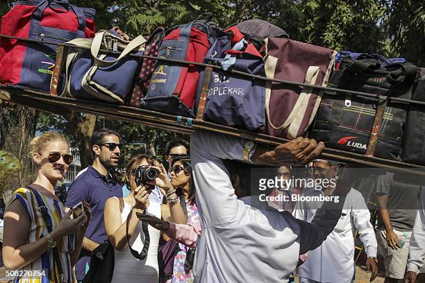 Tourists take photographs of a dabbawalla carrying a crate of lunch bags on his head outside the Churchgate railway station in Mumbai, India, on...