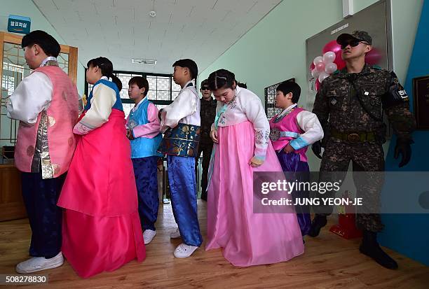 South Korean soldier stands guard next to graduates wearing traditional dress during a graduation ceremony for Taesungdong Elementary School at...