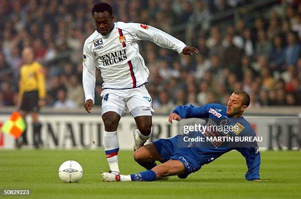 Lyon's Ghanean midfielder Mickael Essien is tackled by Bastia's forward Florian Maurice during their French first league football match, 12 May 2004...