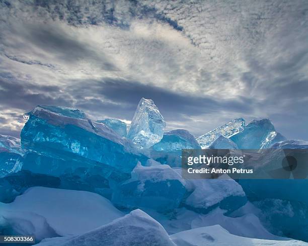 the ice at lake baikal on the background of dramatic sky - eisberg eisgebilde stock-fotos und bilder