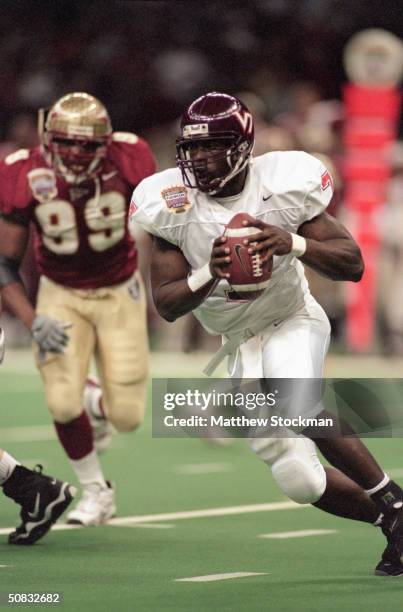 Quarterback Michael Vick of the Virginia Tech Hokies scrambles left and looks to make a play with the ball against the Florida State Seminoles during...