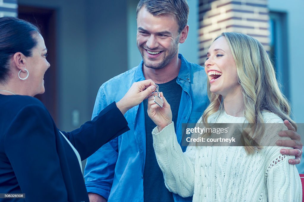 Couple standing in front of a new home with agent.