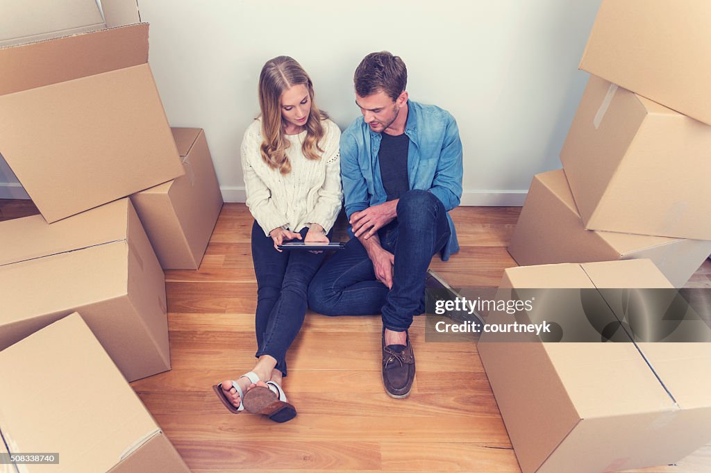 Young couple sitting in new house with packing boxes.