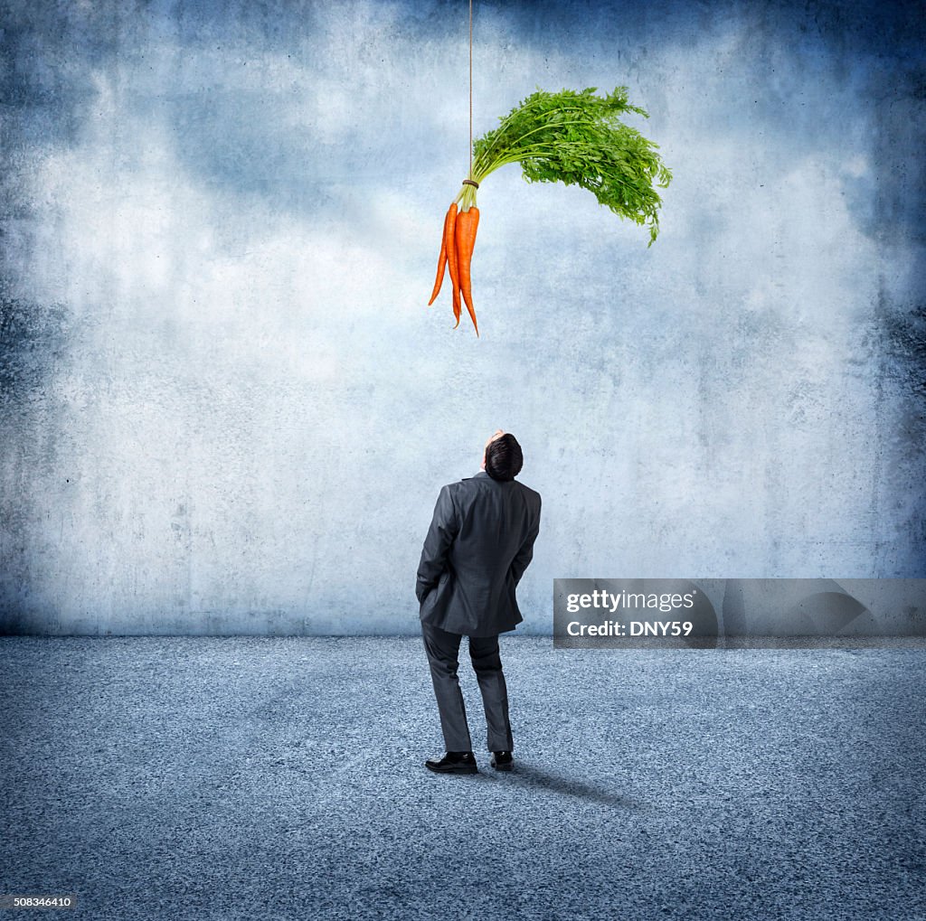 Businessman Looking Up At Carrots Dangling Above Him
