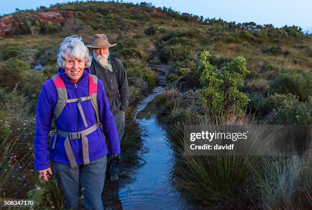 senior couple bushwalking at dawn in a spectacular landscape - female bush photos stockfoto's en -beelden