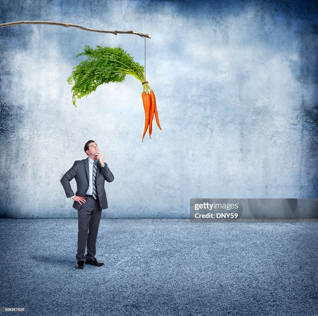 Businessman Looking Up At A Carrot Dangling From A Stick