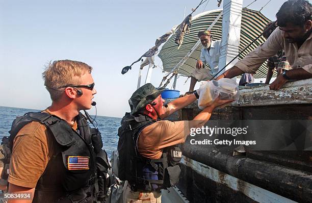 Vessel Board Search and Seizure Team Members from the guided missile cruiser USS Leyte Gulf give fruit and bread to a local fishing dhow's crew after...