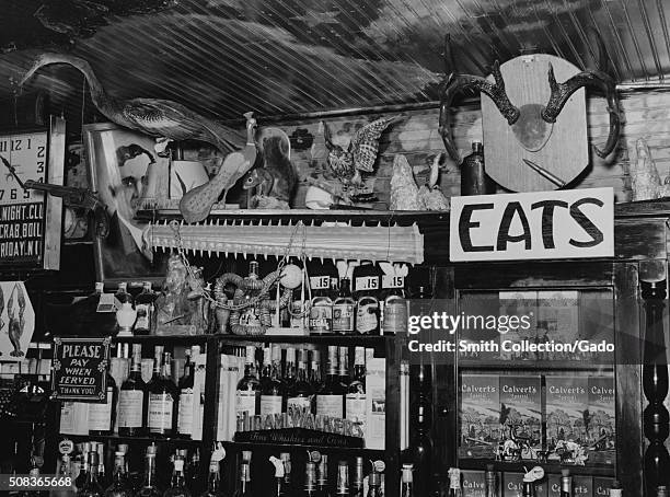 Bar interior featuring a large selection of liquor, decorated in an eclectic manner with stuffed birds, a squirrel, horns, the nose of a sawfish and...