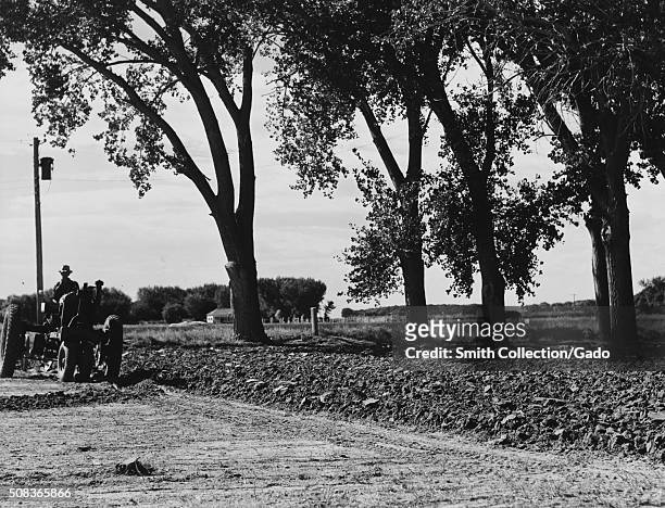 Farmer is seen plowing ground to prepare a garden, a contrast can be seen between the hard, unturned ground and the soil that has been turned, a...