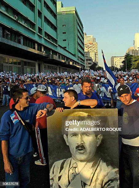 Cubans hold a poster with US President George W. Bush face glued on Adolf Hitler's body during a march in Havana, 14 May 2004. President Fidel Castro...