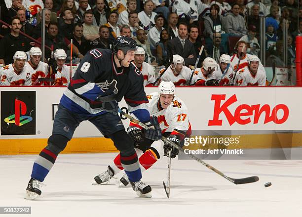 Marek Malik of the Vancouver Canucks passes the puck as Chris Clark of the Calgary Flames tries for the poke check in the first round of the 2004 NHL...