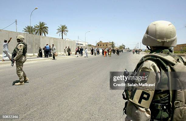 Military Plolice look on as prisoners walk the streets after being released from Abu Ghraib prison on May 14, 2004 in Ba'qoubah, Iraq. The U.S. Army...