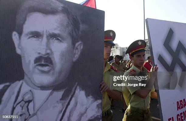 Members of the Cuban Revolutionary Armed Forces hold a poster with a photograph of U.S. President George W. Bush caricatured as Hitler during a march...