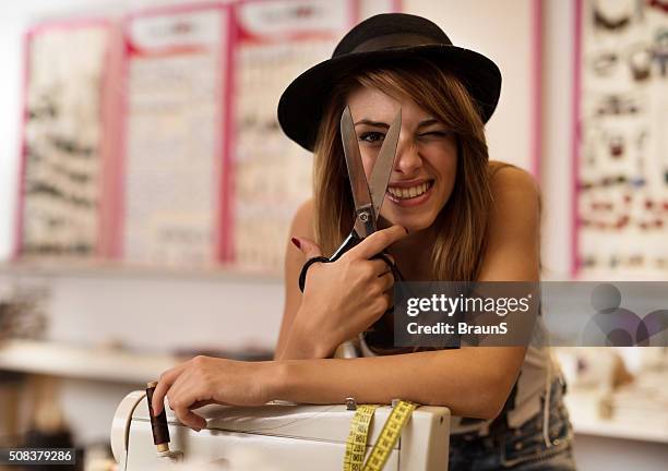 young playful fashion designer squinting through scissors. - tailor stock pictures, royalty-free photos & images