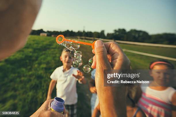 blowing bubbles to children - bubble wand foto e immagini stock