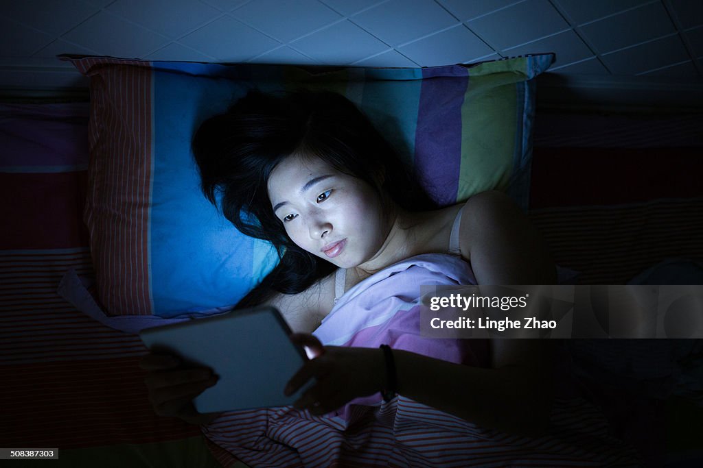 Asian girls reading tablet in bed
