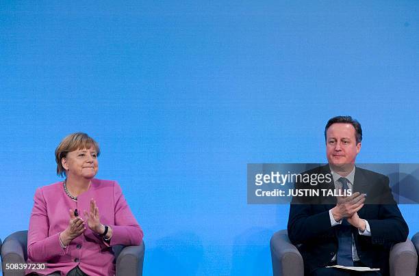 German Chancellor Angela Merkel and British Prime Minister David Cameron applaud as they sit on stage during a press conference at the QEII centre in...