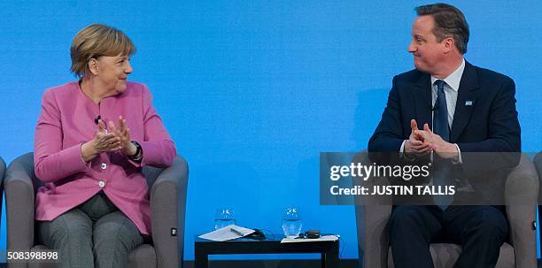 German Chancellor Angela Merkel and British Prime Minister David Cameron looks at each other as they applaud sitting on stage during a press...