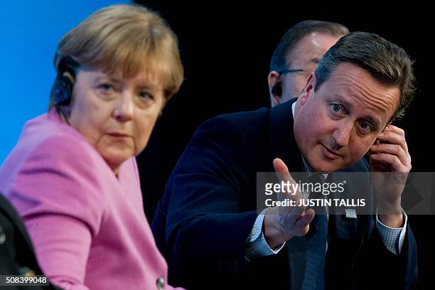 British Prime Minister David Cameron gestures as he sits on stage with German Chancellor Angela Merkel during a press conference at the QEII centre...