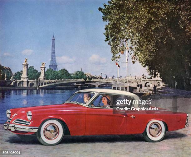 Couple driving their 1953 Studebaker Commander V-8 Starliner hard-top convertible along the Seine River in Paris. Screen print from a photograph.