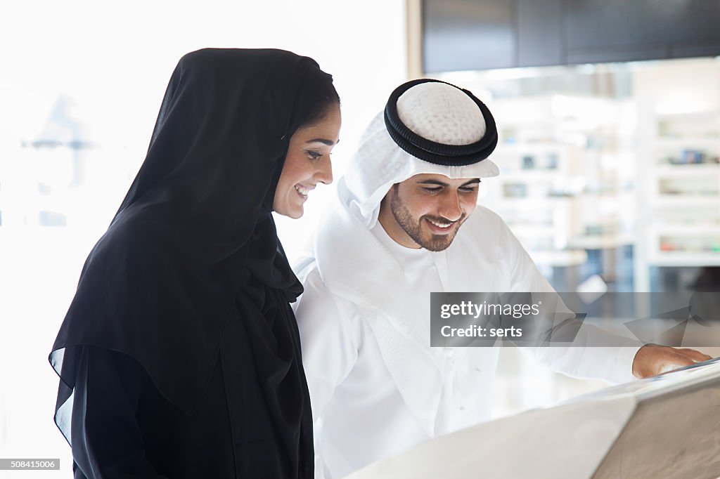 Young Arab couple using information display at mall
