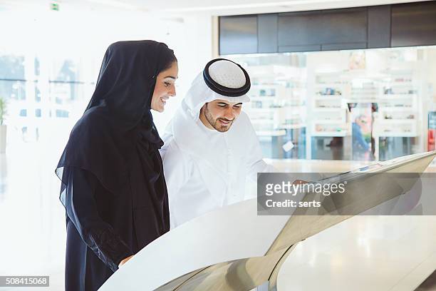 young arab couple using information display at mall - shopping centre screen stock pictures, royalty-free photos & images