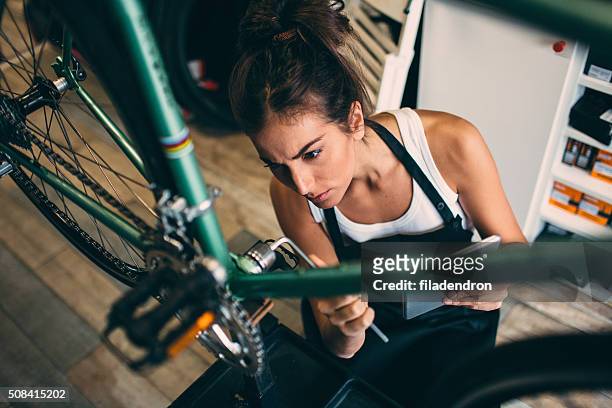 junge frau reparieren ein fahrrad - fahrrad reparieren stock-fotos und bilder