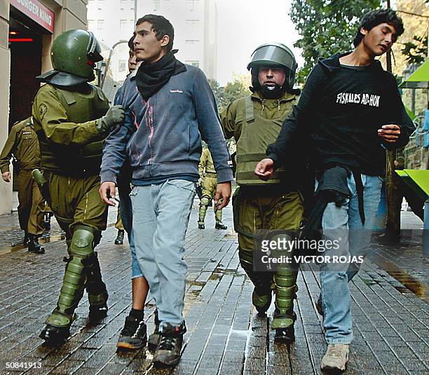 Policias anti-disturbios arrestan a unos manifestantes en las cercanias del palacio presidencial de La Moneda en Santiago, el 15 de mayo de 2004....