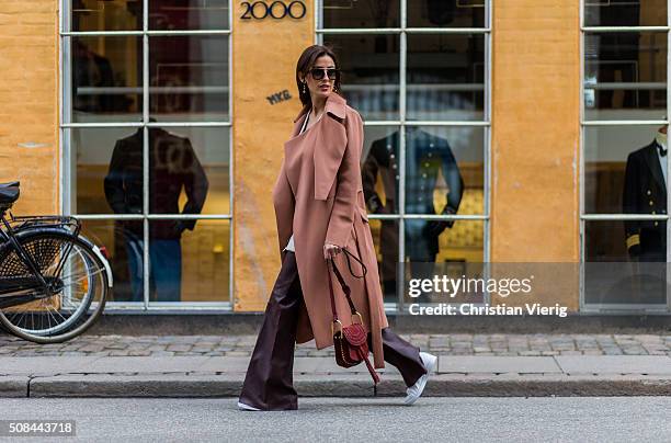 Fashion blogger Sylvia Haghjoo wearing Chloe Hudson bag, Adidas sneaker, Celine earrings and sunglasses, By Malene Birger pants, top and coat during...