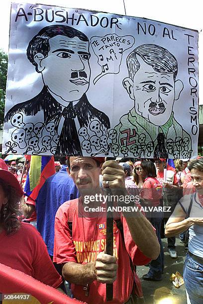 Supporter of Venezuelan President Hugo Chavez holds a poster with a caricature comparing US President George W. Bush and Adolf Hitler during a march...