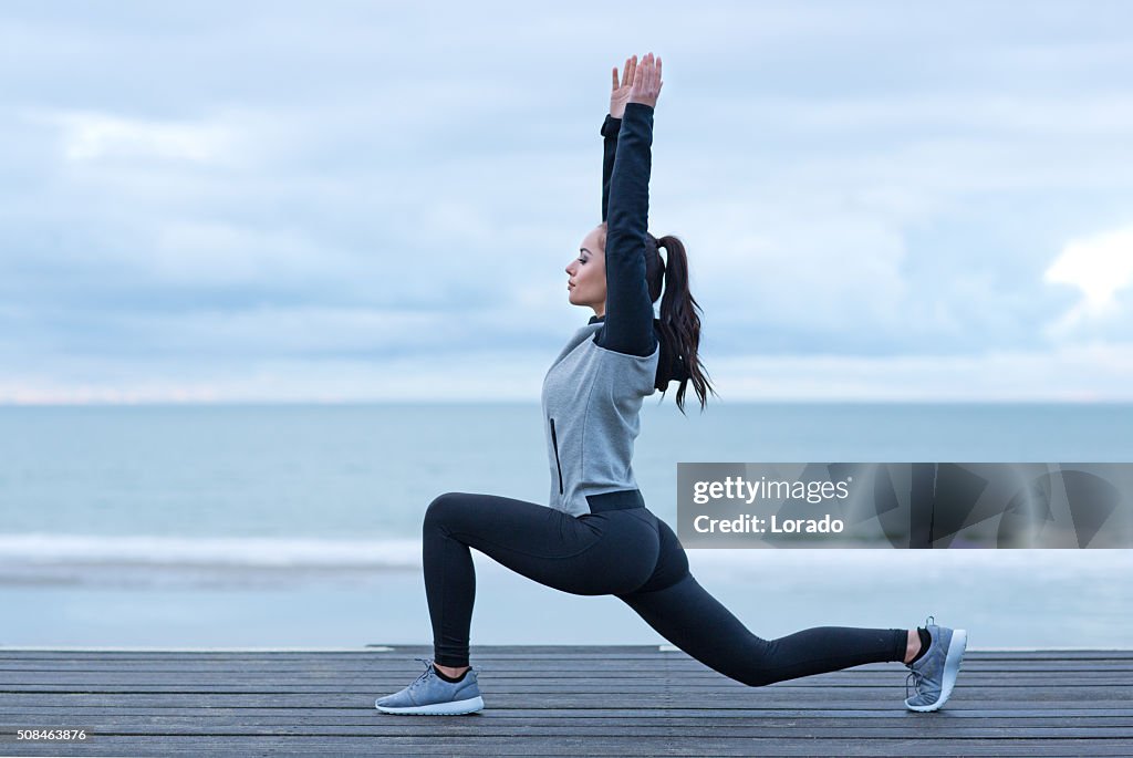 Schöne Brünette Frau auf einem Strand trägt Sport Kleidung