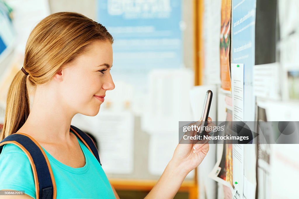 Girl Photographing Document On Bulleting Board Through Smart Phone