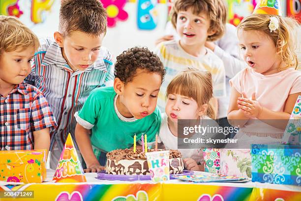 bambini soffiare le candele di compleanno. - children birthday party foto e immagini stock