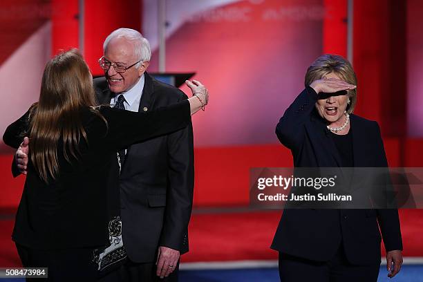 Democratic presidential candidate former Secretary of State Hillary Clinton looks out at the crowd as U.S. Sen. Bernie Sanders is hugged by his wife,...