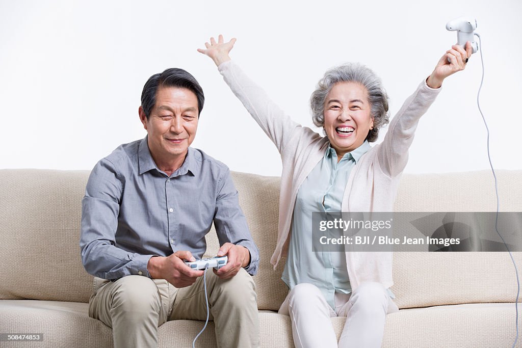 Senior couple playing video game in living room