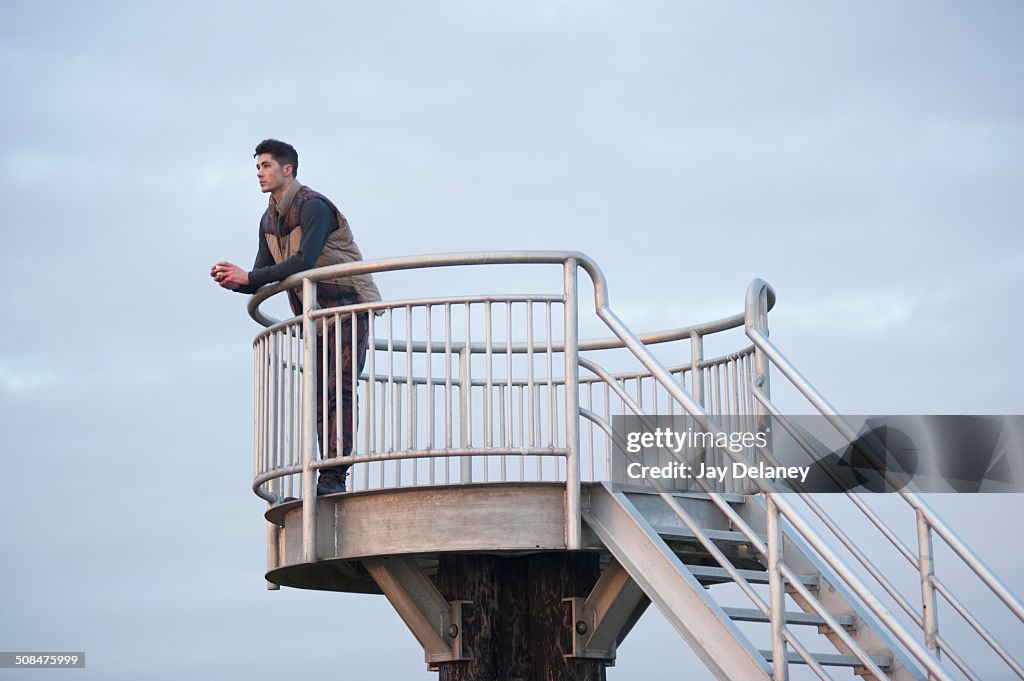 Full length of thoughtful man leaning on railing at tower