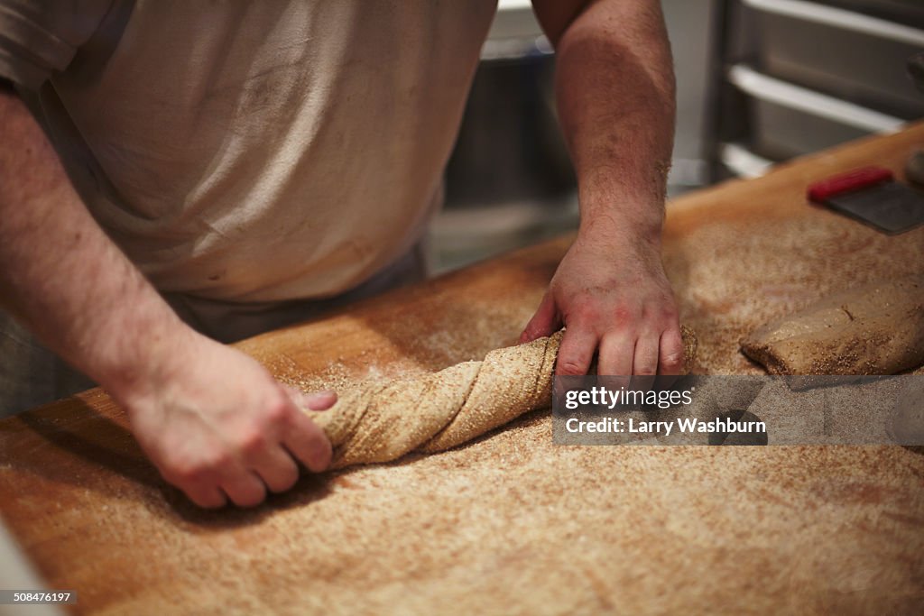 Mid section of man preparing bread at kitchen counter