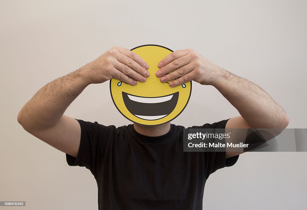 Man holding with hands covering the eyes of a happy emoticon face