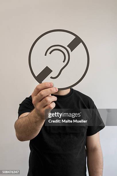 man holding a hear no evil sign emoticon in front of his face - 3 wise monkeys emoji stock pictures, royalty-free photos & images