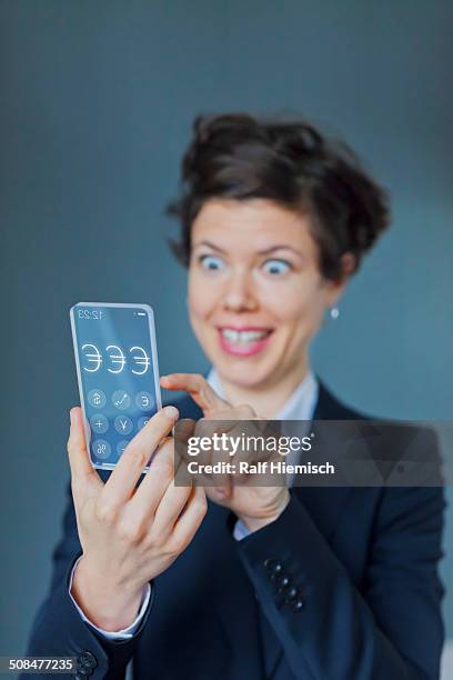 surprised businesswoman using futuristic transparent mobile with euro sign - smartphone euro stockfoto's en -beelden